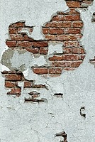 Old wall with bricks showing through the plaster